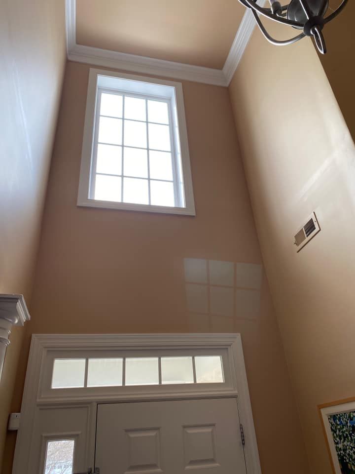 Tall entryway with two windows, painted peach. White trim around the door and upper window.