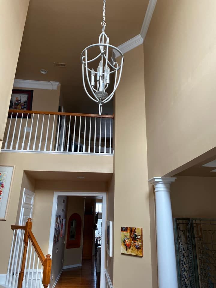 High-ceilinged foyer with a chandelier, balcony, staircase, and tan walls.