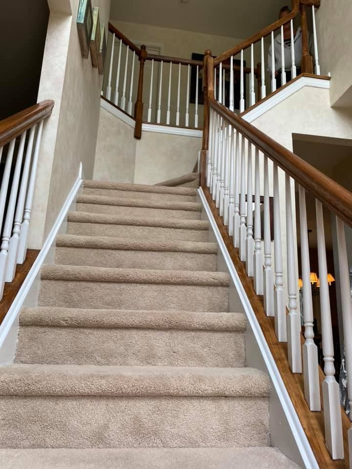 Staircase with carpeted steps, white balusters, and wooden handrails leading upwards to a second floor.