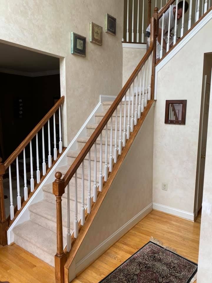 Staircase with wooden railing and white spindles, leading up to a landing. Light tan walls, carpeted steps.