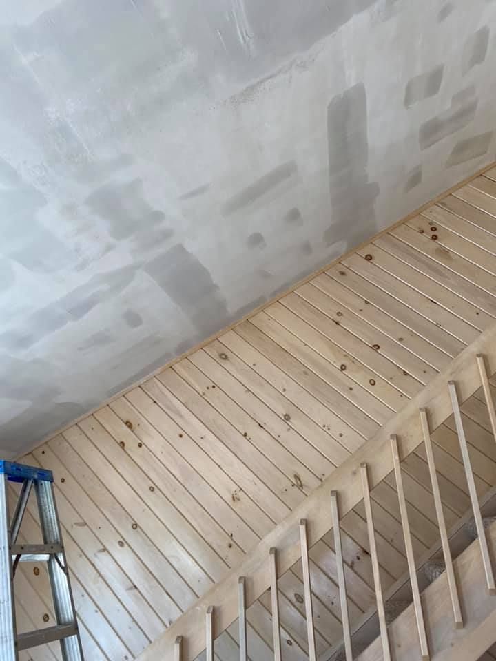 Wooden slatted wall alongside a staircase, with a gray ceiling above.