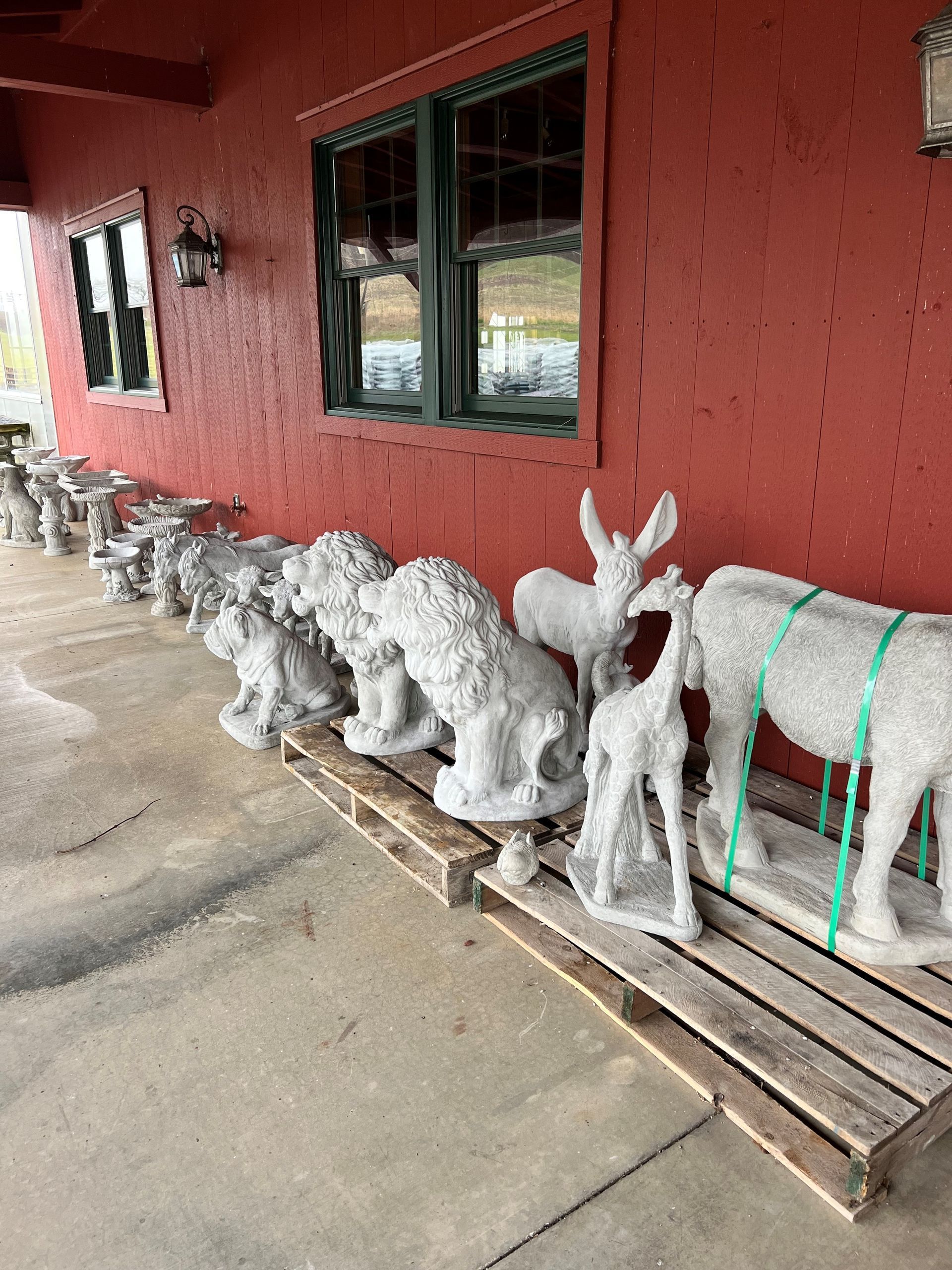 A row of concrete statues of animals are sitting on wooden pallets