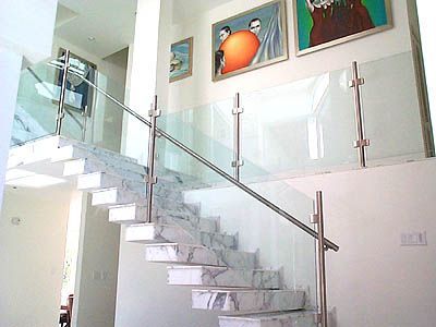 A staircase with a glass railing and paintings on the wall