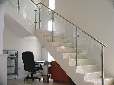A staircase with a glass railing and a black chair