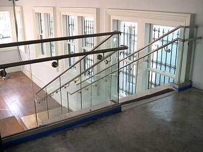 A staircase with a glass railing in a building with lots of windows.