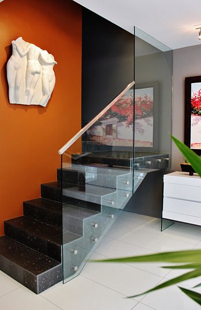 A staircase with a glass railing and a statue on the wall