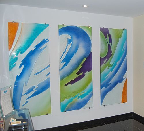 Three colorful paintings are hanging on a white wall