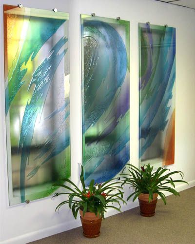 Three potted plants are in front of three paintings on a wall