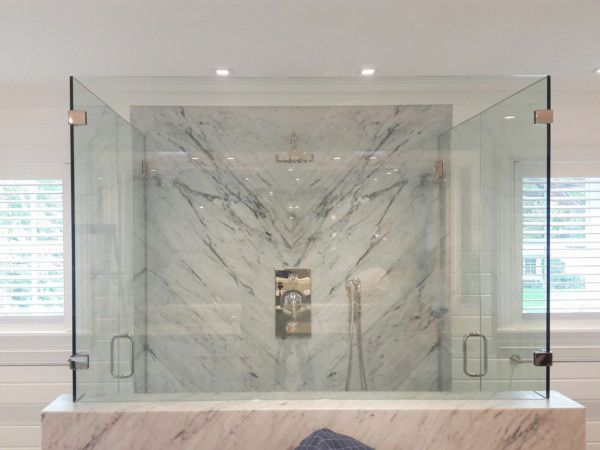 A bathroom with a glass shower door and a marble counter top.
