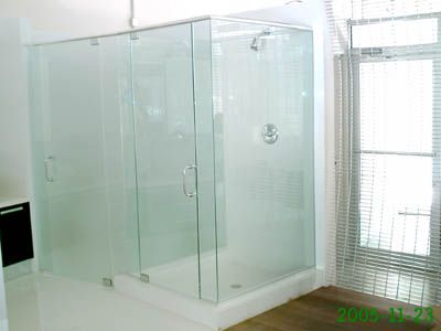 A bathroom with a walk in shower with sliding glass doors