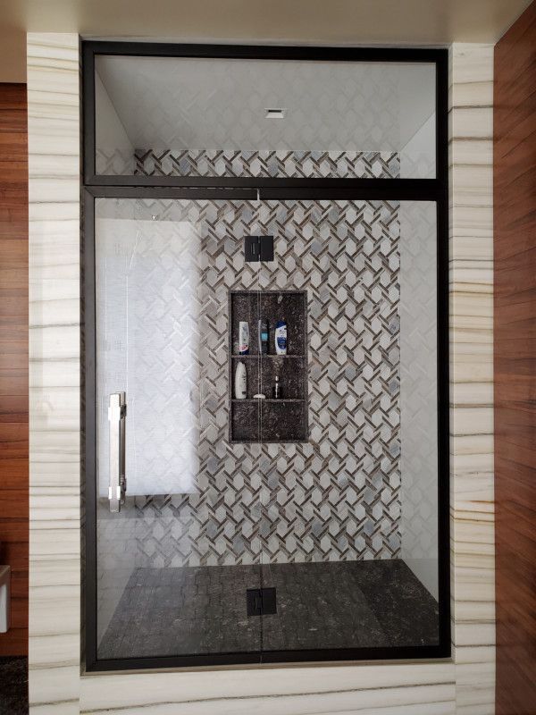 A bathroom with a walk in shower with a glass door.
