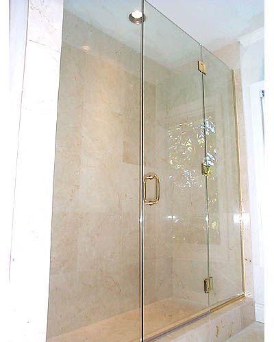 A bathroom with a glass shower door and a marble wall.