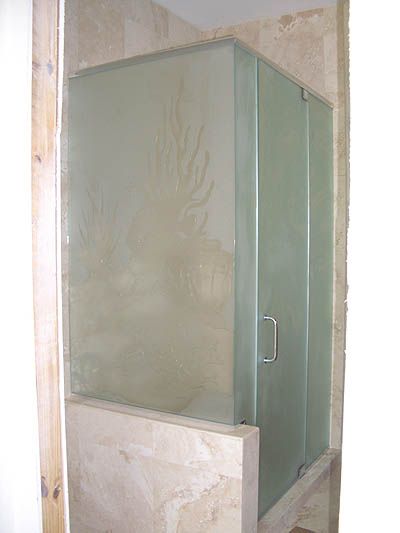 A bathroom with a glass shower door and a marble wall.