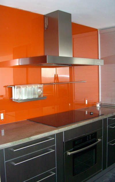 A kitchen with orange walls and a stove top oven