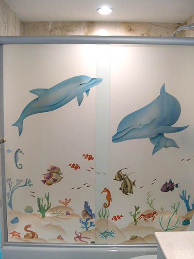 A shower door with dolphins and fish on it
