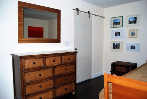 A bedroom with a dresser and a mirror on the wall