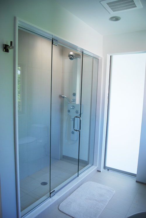 A bathroom with a sliding glass shower door and a white rug.