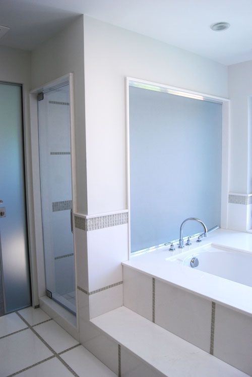 A bathroom with a tub a shower and a mirror