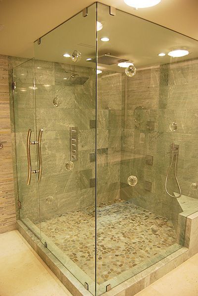 A bathroom with a walk in shower with a glass door.