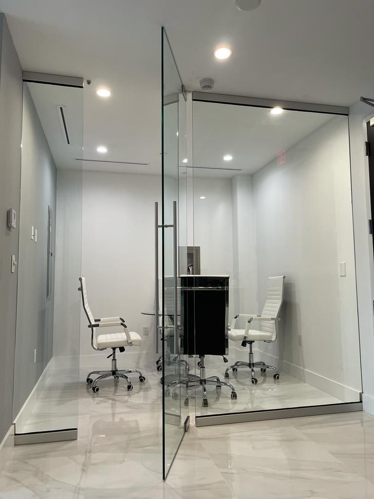 A conference room with a glass wall and white chairs.