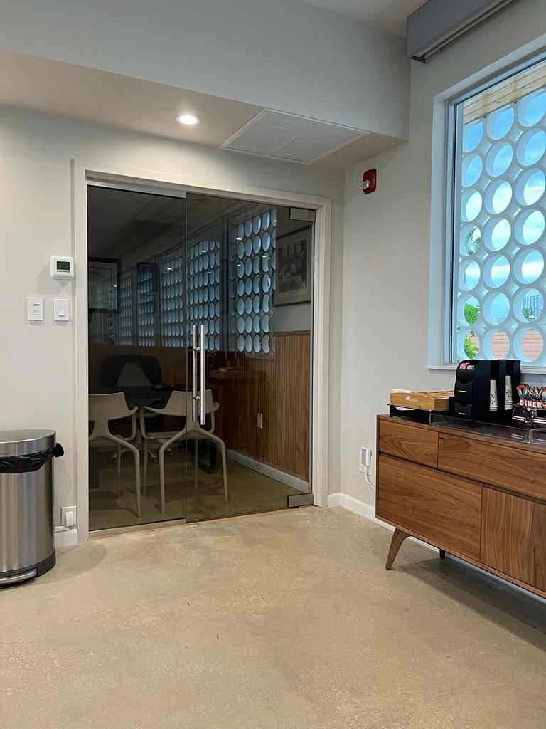 A room with a glass door leading to a conference room.