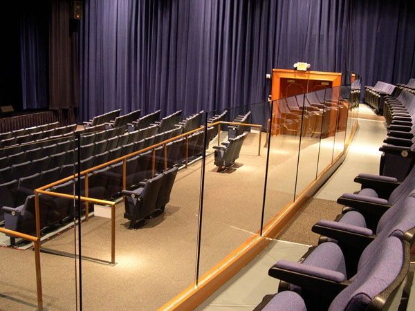 An auditorium with purple seats and a glass railing