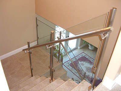 A staircase with a glass railing and a rug on the floor.