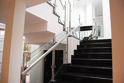 A staircase with black steps and a glass railing in a house.