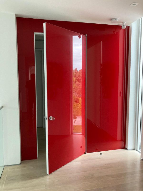 A red door is open in a room with a white wall.