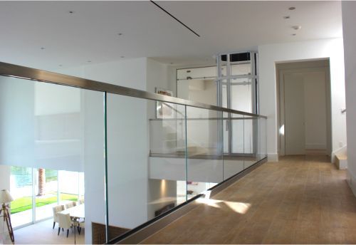 A hallway with a glass railing leading to a staircase