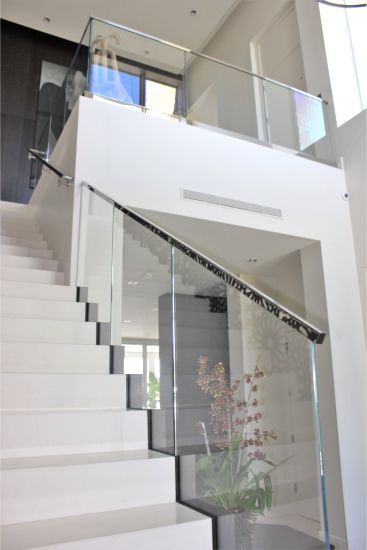 A white staircase with a glass railing in a house