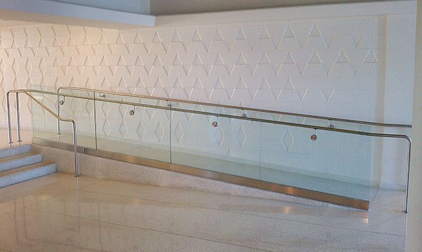 A staircase with a glass railing and a white wall.