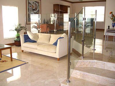 A living room with a couch and stairs with a glass railing