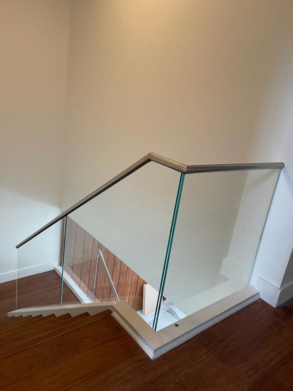 A staircase with a glass railing and a wooden floor.