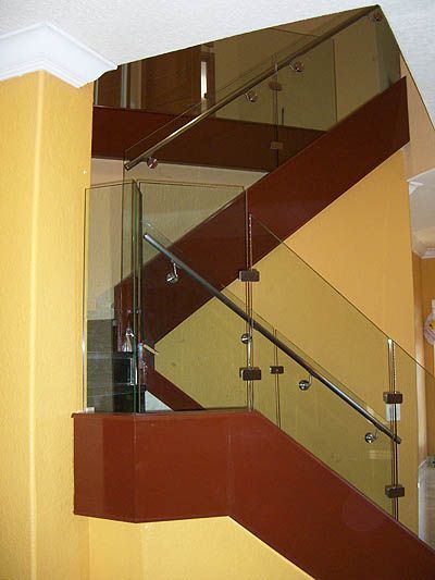 A staircase with a glass railing and a yellow wall