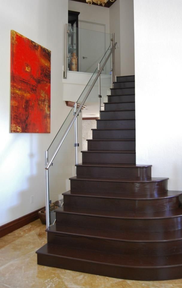 A staircase with a glass railing and a red painting on the wall