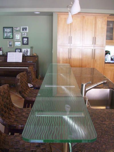 A kitchen with a glass counter top and a sink
