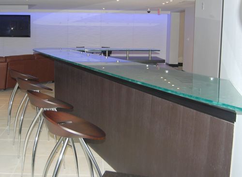 A bar with a glass top and wooden stools