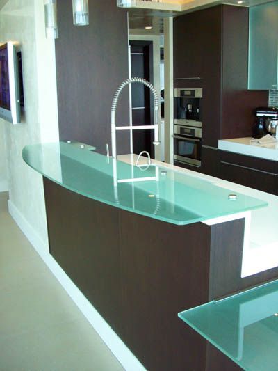 A kitchen with a glass counter top and a faucet