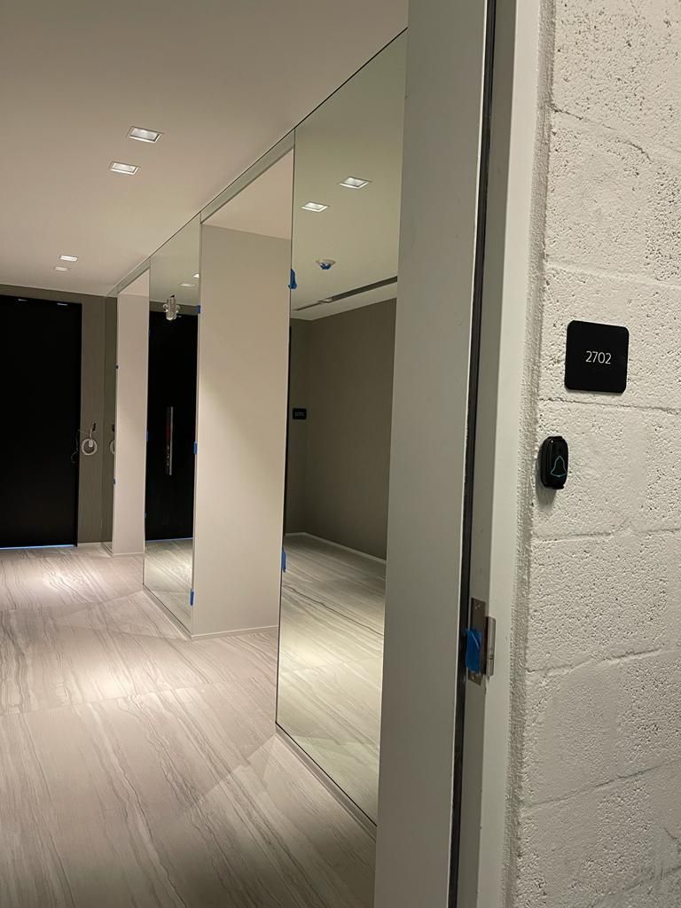 A hallway with a lot of mirrors on the wall and a door.