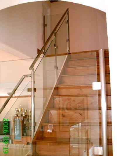 A wooden staircase with a clear glass railing