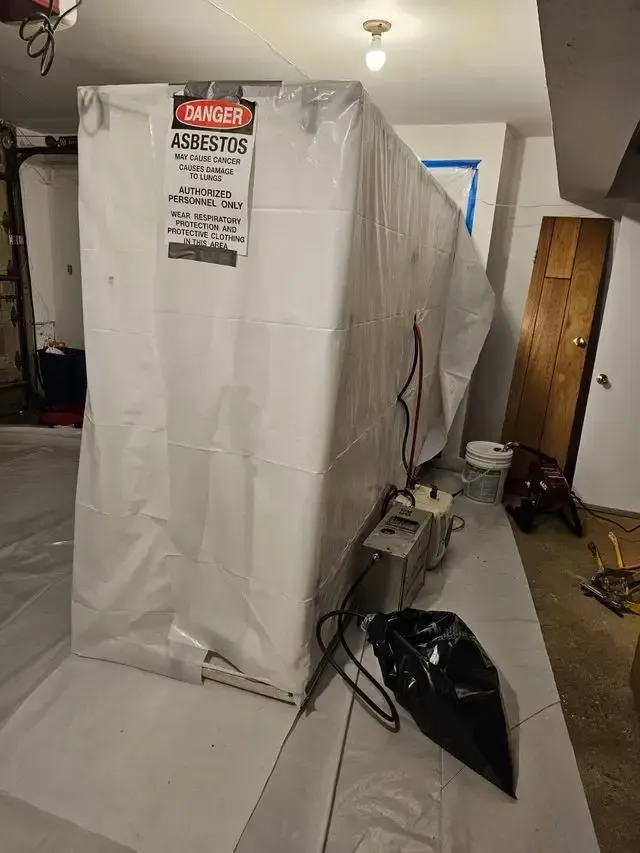 A large white tarp is covering a room in a basement.