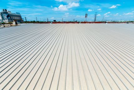 Wide empty beach with white sand, blue sky, and a distant pier on the horizon