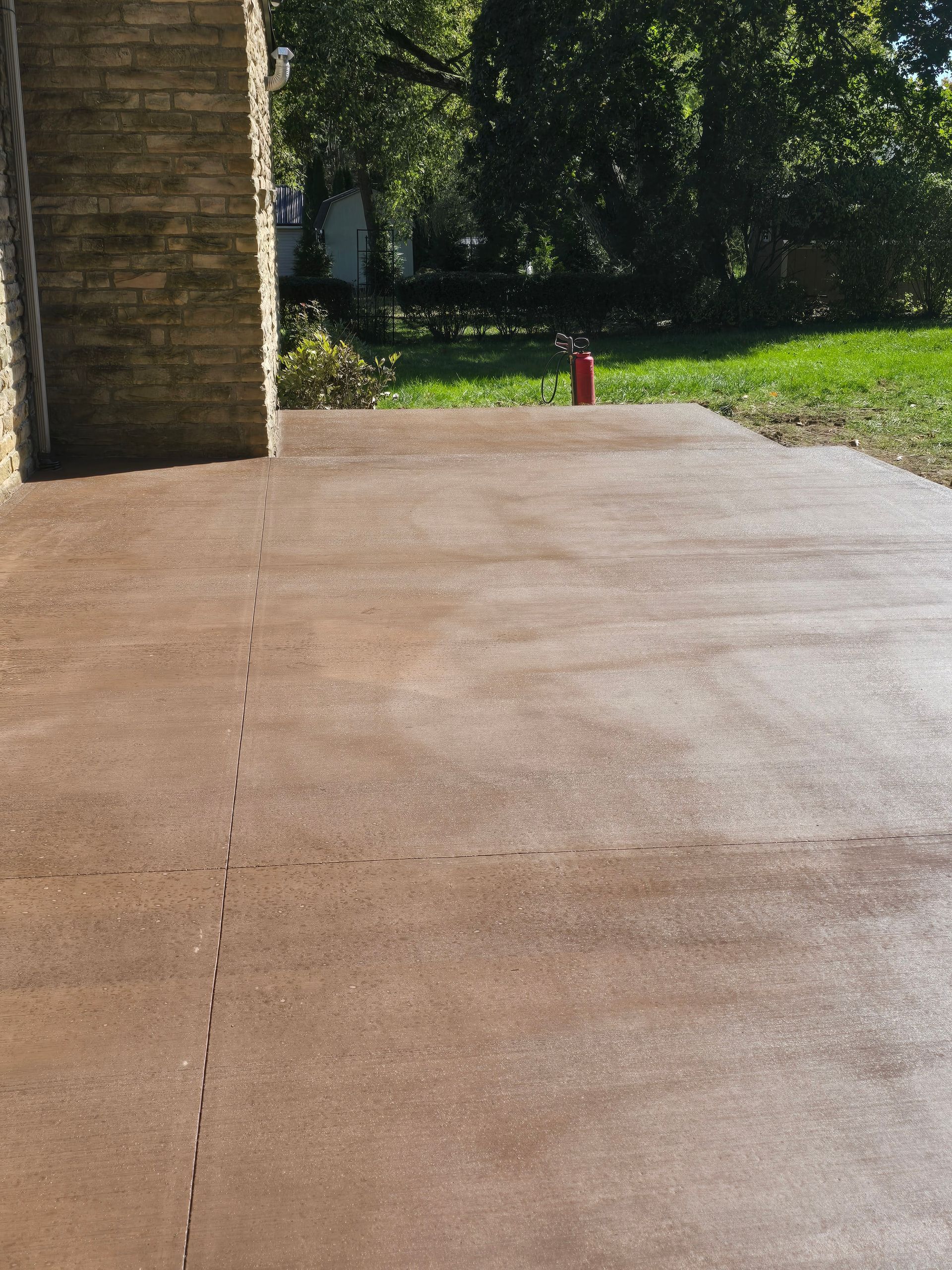 A brown concrete driveway with a brick wall in the background.