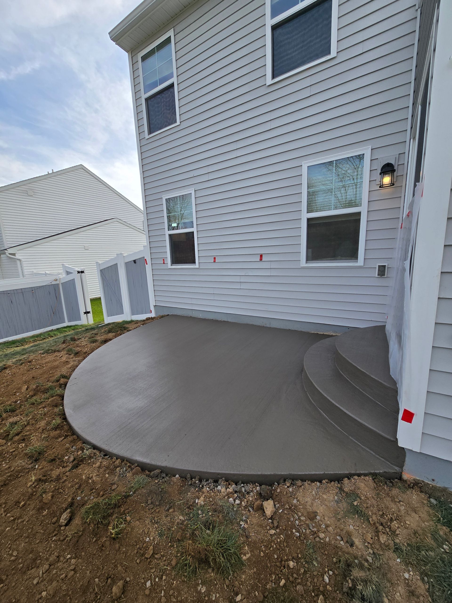 A large white house with a concrete patio in front of it.