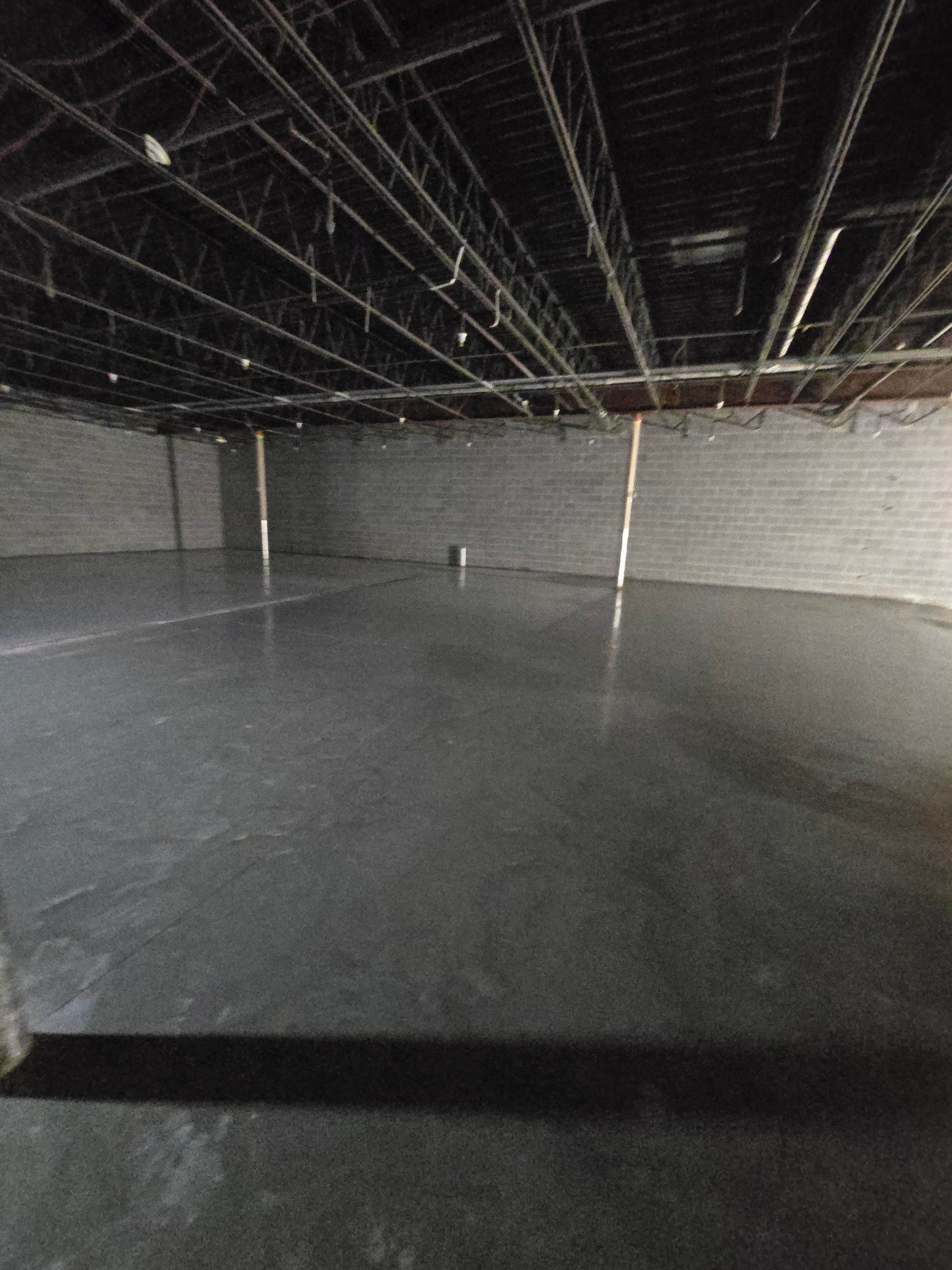 A large empty room with a concrete floor and a metal ceiling.