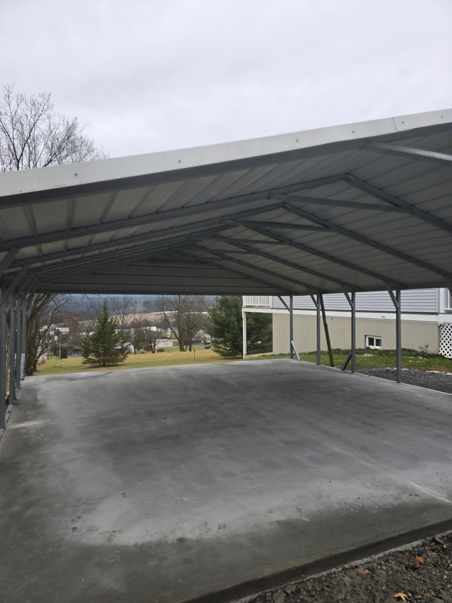 An empty parking lot with a carport in the background.