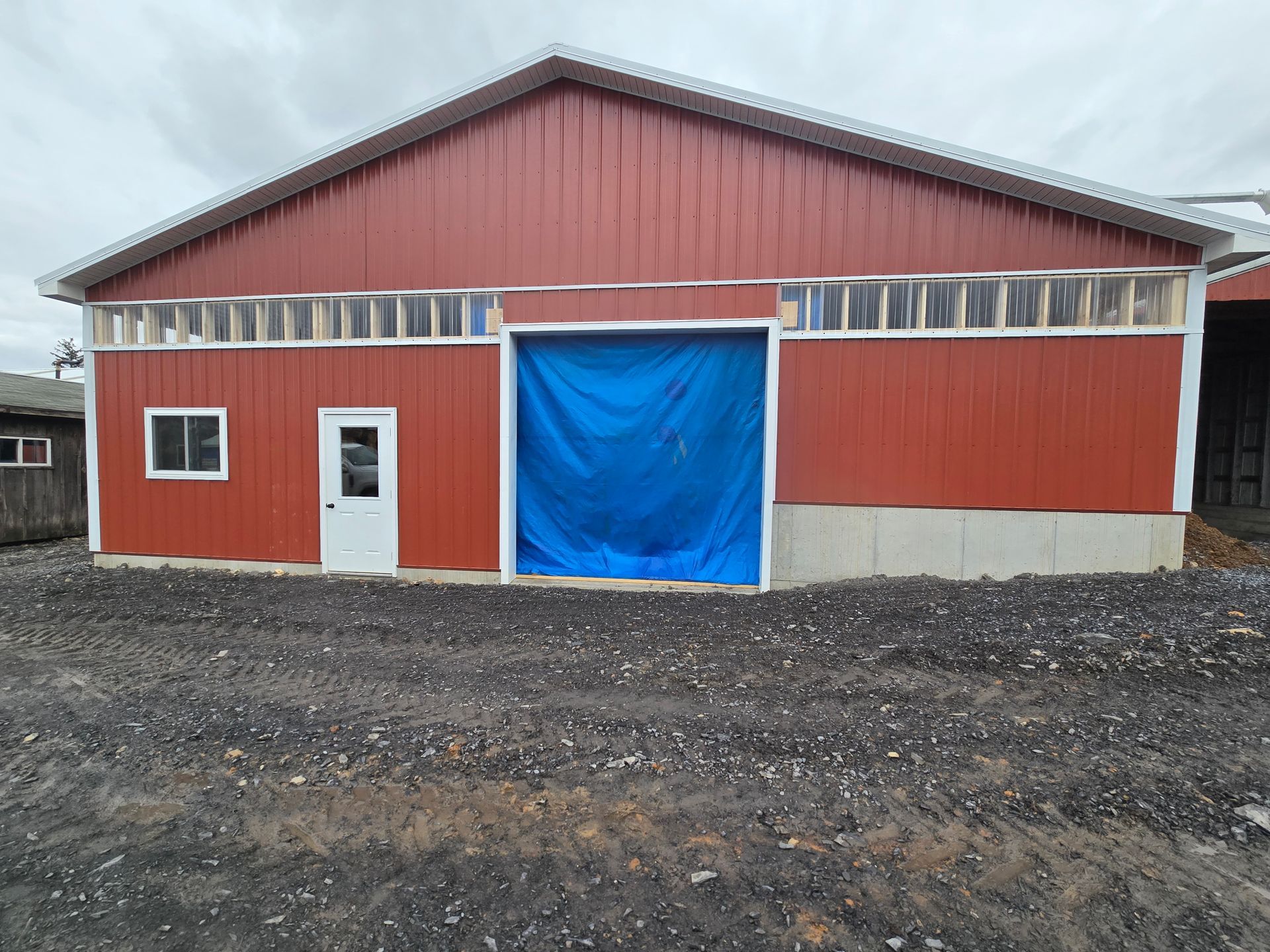 A red barn with a blue tarp covering the door.