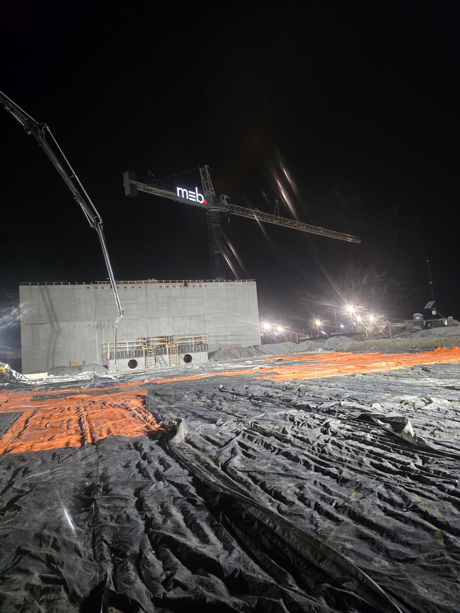 A large concrete structure is being built at night.