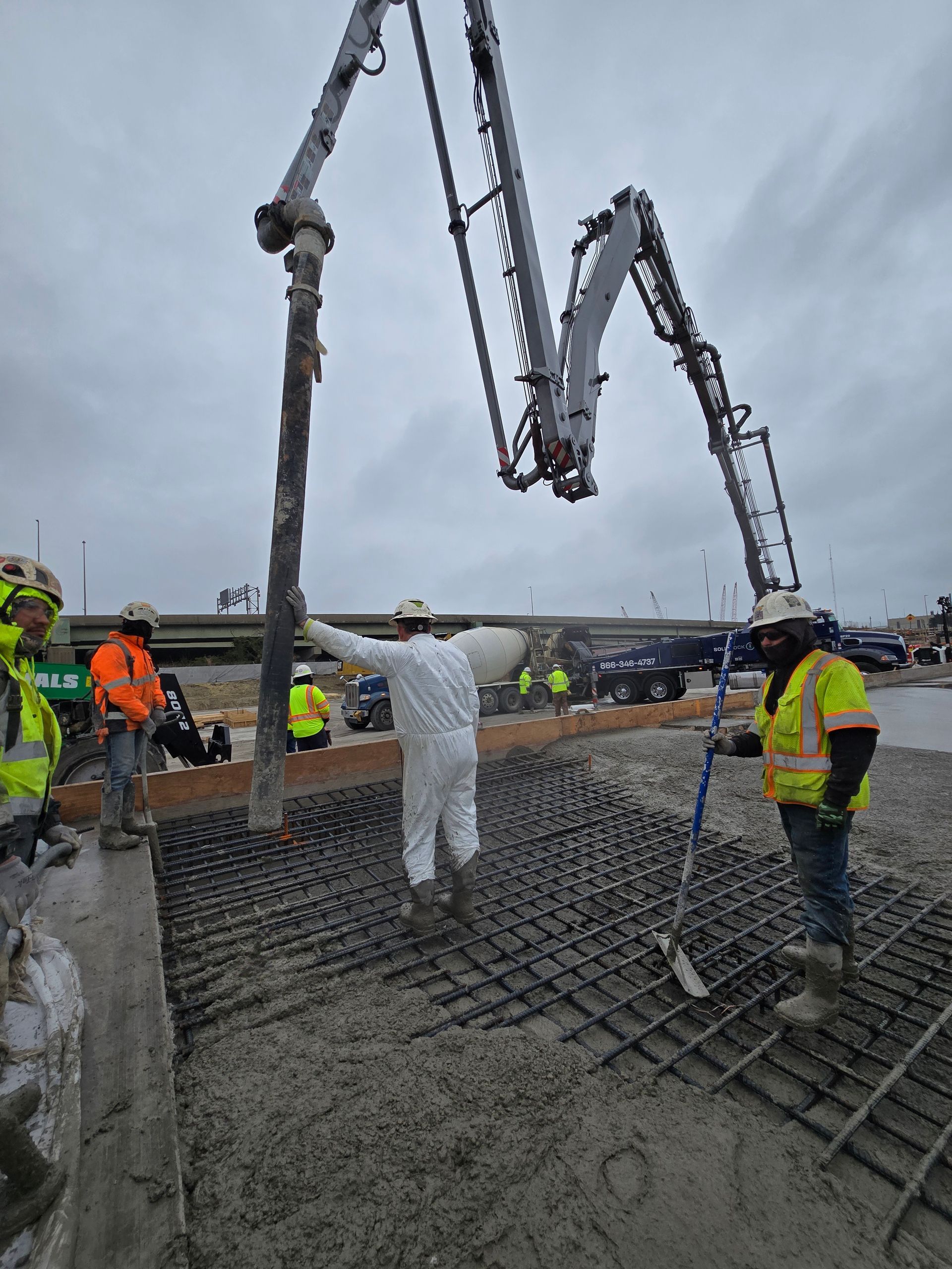 A group of construction workers are pouring concrete on a construction site.